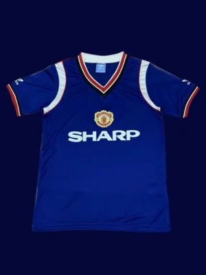 front view of Manchester United away blue retro jersey (1984) with vintage stripes.