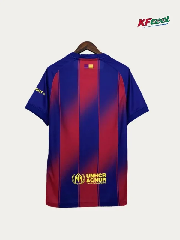 Blue and red striped jersey on a hanger, back view, with UNHCR logo near the hem and a small flag patch at the upper back.