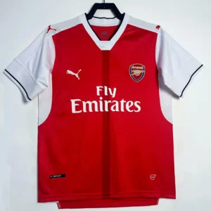 Arsenal 2016/17 Home Jersey Fan Version - Front View Arsenal home football jersey red body with white sleeves, crest on left chest and Fly Emirates sponsor in white text.
