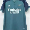 Arsenal 2023/24 Third Jersey Fan Version - Front View Arsenal teal away jersey with Emirates Fly Better sponsor and Adidas logo, hanging on a hanger.