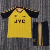 Arsenal 1988/90 Retro Away Kids Kit Fan Version - Front View - KFCool – Football Jerseys & Soccer Kits Store Yellow soccer jersey with navy sleeves, red trim, and JVC sponsor; includes Adidas logos and matching navy shorts with yellow stripes.