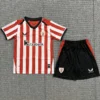 Athletic Bilbao 2026/27 Home Kids Kit Fan Version - Front View - KFCool – Football Jerseys & Soccer Kits Store Red-and-white striped soccer jersey with black collar and Kutxabank sponsor, crest on left chest, paired with black shorts with red side panels.