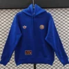 Blue hoodie on a hanger featuring two small patches on the chest and a brown label on the front pocket for branding details.