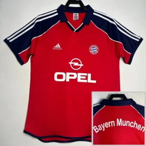 Red Bayern Munich football jersey with blue sleeves featuring white stripes; displays Adidas logo, Opel sponsor, and Bayern crest on the chest.