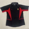 Belgium 2002 Retro Away Jersey Fan Version - Front View Black polo-style sports jersey with red geometric panels and a Belgian national team crest on the chest, Nike swoosh on the opposite side, laid flat on a light background