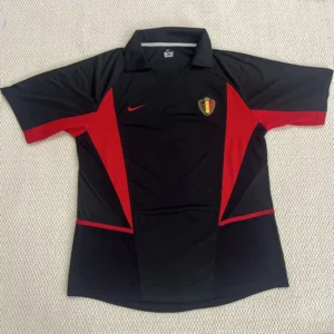 Black polo-style sports jersey with red geometric panels and a Belgian national team crest on the chest, Nike swoosh on the opposite side, laid flat on a light background