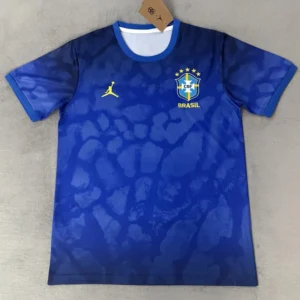 Blue Brazil national football team jersey with CBF crest and five stars, featuring the yellow Jumpman logo and 'BRASIL' text on the chest.