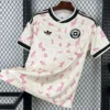 Chile 2026/27 Away Jersey Fan Version - Front View White soccer jersey hanging on a hanger: white with pink blossom pattern, black trim, and Adidas logo with a Chile football federation crest on the chest.