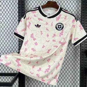 Chile 2026/27 Away Jersey Fan Version - Front View White soccer jersey hanging on a hanger: white with pink blossom pattern, black trim, and Adidas logo with a Chile football federation crest on the chest.