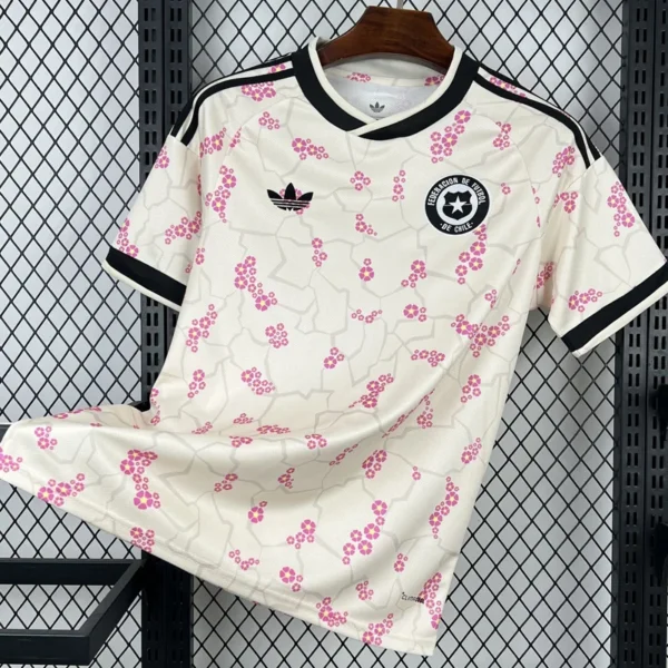 Chile 2026/27 Away Jersey Fan Version - Front View White soccer jersey hanging on a hanger: white with pink blossom pattern, black trim, and Adidas logo with a Chile football federation crest on the chest.