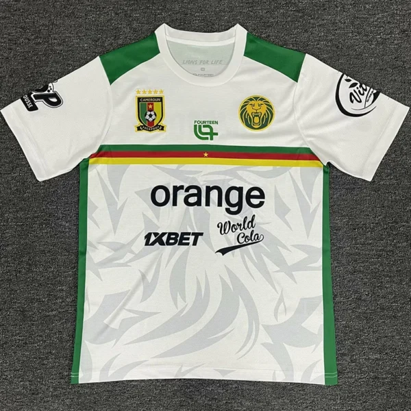 White soccer jersey with green shoulders and sides, featuring Cameroon crest, a lion emblem, and sponsor logos (Orange and World Cola).