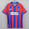 Red and blue striped soccer jersey on a hanger with Churchill sponsor logo in the center and team crest on the chest.
