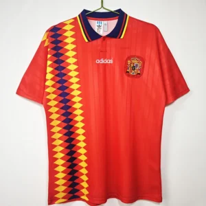Red Spain national team soccer jersey with a bold yellow and navy diamond stripe along the left side and Adidas logo in the center.