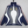Navy blue Adidas France national team training jacket with white center panels, red stripes on sleeves, hanging on a grid-pattern backdrop.