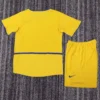 Back view of a bright yellow soccer jersey with blue trim and matching shorts on a gray carpet, Nike logo visible on the shorts.