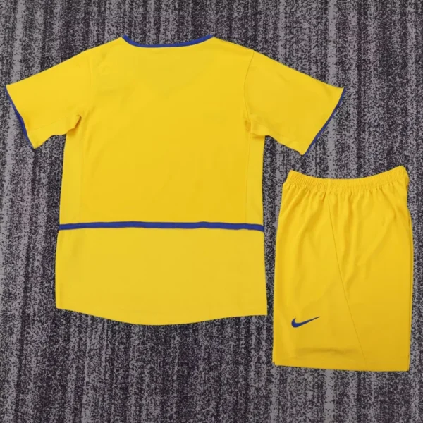 Back view of a bright yellow soccer jersey with blue trim and matching shorts on a gray carpet, Nike logo visible on the shorts.