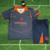 Inter-style dark gray and orange soccer jersey with matching shorts laid on grass field.