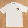 White short-sleeve Italy soccer jersey with tricolor shield crest on the left chest and blue Kappa logos on the sleeves.