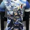 Japan 2026/27 Blue Special Edition Jersey Player Version - Front View T-shirt with a blue-and-white dragon and armored samurai wielding a sword, plus a Japan JFA crest on the chest, on a rack background.
