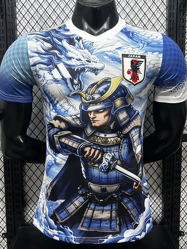Japan 2026/27 Blue Special Edition Jersey Player Version - Front View T-shirt with a blue-and-white dragon and armored samurai wielding a sword, plus a Japan JFA crest on the chest, on a rack background.