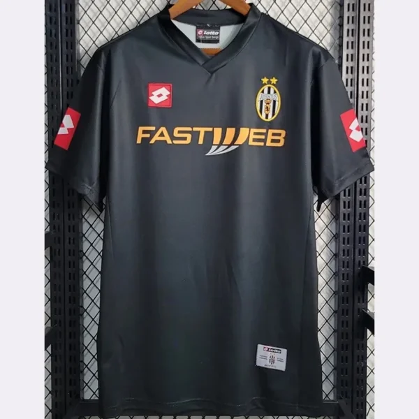 Juventus black football jersey on a hanger with the club crest, two gold stars, and an orange FASTWEB sponsor logo across the chest.