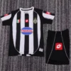 Juventus 2002/03 Retro Home Kids Kit Fan Version - Front View - KFCool – Football Jerseys & Soccer Kits Store Black and white vertically striped soccer jersey laid flat, with TamOil sponsor logo and Juventus-style crest, shown with black shorts nearby.