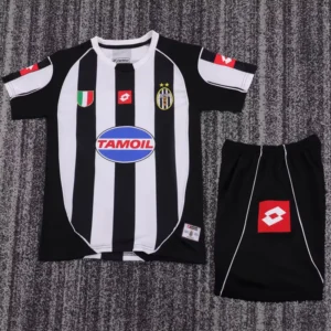 Black and white vertically striped soccer jersey laid flat, with TamOil sponsor logo and Juventus-style crest, shown with black shorts nearby.
