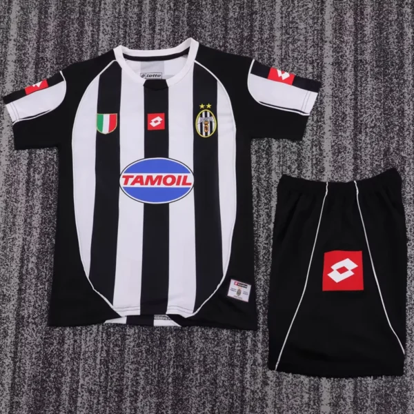 Juventus 2002/03 Retro Home Kids Kit Fan Version - Front View - KFCool – Football Jerseys & Soccer Kits Store Black and white vertically striped soccer jersey laid flat, with TamOil sponsor logo and Juventus-style crest, shown with black shorts nearby.