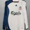 White and blue long-sleeve Liverpool FC jersey on a hanger, featuring Adidas logo, Liverpool crest, and Carlsberg sponsor across the chest