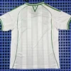 Back view of a white sports jersey with light gray vertical stripes and green trim along the shoulders and sides.