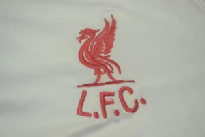 Liverpool 1985/86 Retro Away Jersey Fan Version - Front View Red embroidered Liverpool FC liver bird logo with 'L.F.C.' on white fabric.