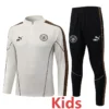 Kids' Manchester City training tracksuit: white top with crest and black pants with sidestrip detail and matching branding.