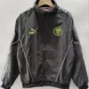 Manchester City 2026/27 Windbreaker - Front View - KFCool – Football Jerseys & Soccer Kits Store Black Manchester City track jacket on a hanger, with neon crest on the left chest, neon Puma King logo on the right, white piping, and a patterned sleeve design.