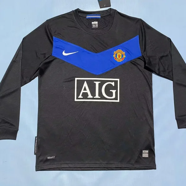 Black Manchester United long-sleeve jersey with a blue chevron across the chest, Nike swoosh, crest, and AIG sponsor logo.