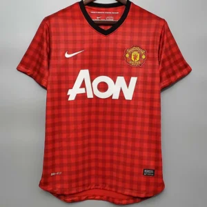Manchester United 2012/13 Retro Home Jersey Fan Version - Front View Manchester United red home jersey on a hanger with checkered pattern, crest, Nike swoosh, and AON sponsor logo.
