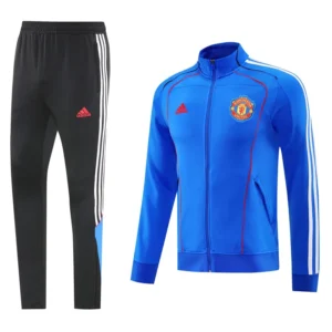 Black Adidas track pants with white side stripes paired with a blue Manchester United track jacket featuring red stitching and the club crest on the chest.