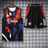 Manchester United training kit on display: black sleeveless jersey with red/blue camouflage pattern, Tezos logo, and club crest beside matching shorts with adidas stripes and crest on a grid backdrop.