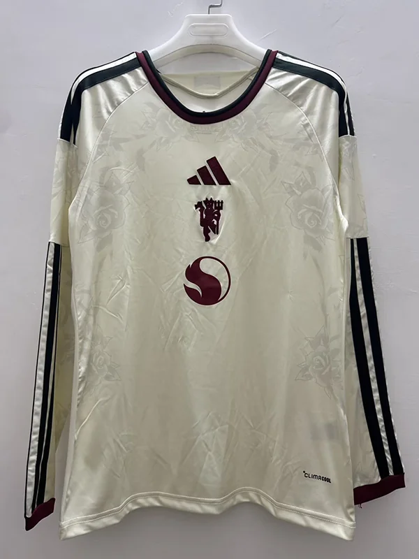 Cream Adidas football jersey on a hanger: maroon Adidas logo, England crest with lions, and a circular sponsor emblem on the chest; long sleeves with dark trim.