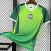 Nigeria 2026/27 Home Jersey Fan Version - Front View Bright green football jersey with white trim and Nike swoosh, hanging on a wooden hanger in front of a metal grid background.