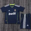 Real Madrid 2010/11 Retro Away Kids Kit Fan Version - Front View Navy Real Madrid football jersey with neon green trim and matching shorts on a textured surface, featuring bwin sponsor and Adidas logos