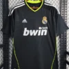 Real Madrid 2010/11 Retro Away Jersey Fan Version - Front View Real Madrid football jersey in black with neon lime piping on a hanger, featuring sponsor bwin and club crest.