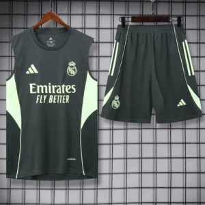 Real Madrid training jersey and shorts set in dark gray with neon green panels, sponsor Emirates Fly Better, hanging on a grid wall (product photo).