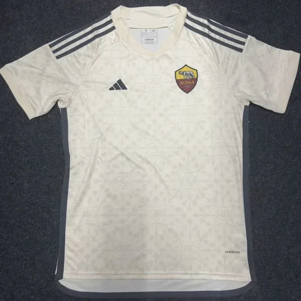 White AS Roma football jersey with dark side panels, three black stripes on shoulders, and club crest on the chest laid flat.