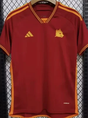 Roma 2023/24 Home Jersey Fan Version - Front View Maroon Adidas sports jersey hanging on a hanger with yellow trim and a wolf crest on the left chest.