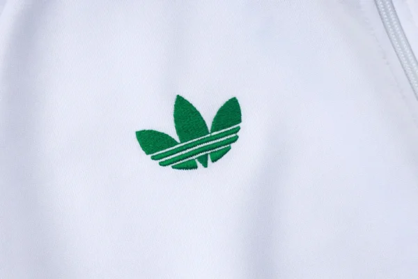 Senegal 2026/27 White Jacket Tracksuit - Model View - KFCool – Football Jerseys & Soccer Kits Store White fabric with an embroidered green Adidas trefoil logo on it.