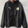 Black zip-up windbreaker with a hood, featuring a white Puma logo on the left chest and a circular colorful crest on the right chest with two stars above it.